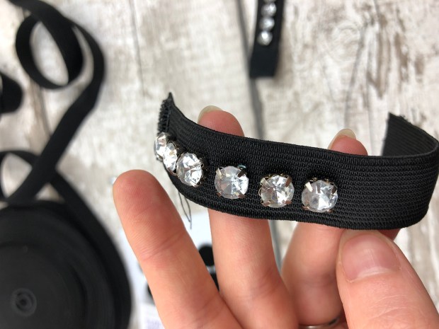 ladies hand showing jewels sewn onto black elastic