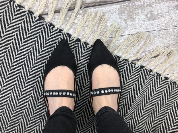 ladies feet wearing black jewelled pumps on monochrome rug